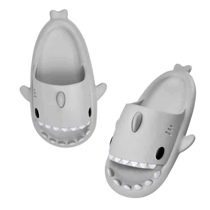 Grå flip-flops i form av en haj med vita tänder och svarta ögon mot en vit bakgrund
